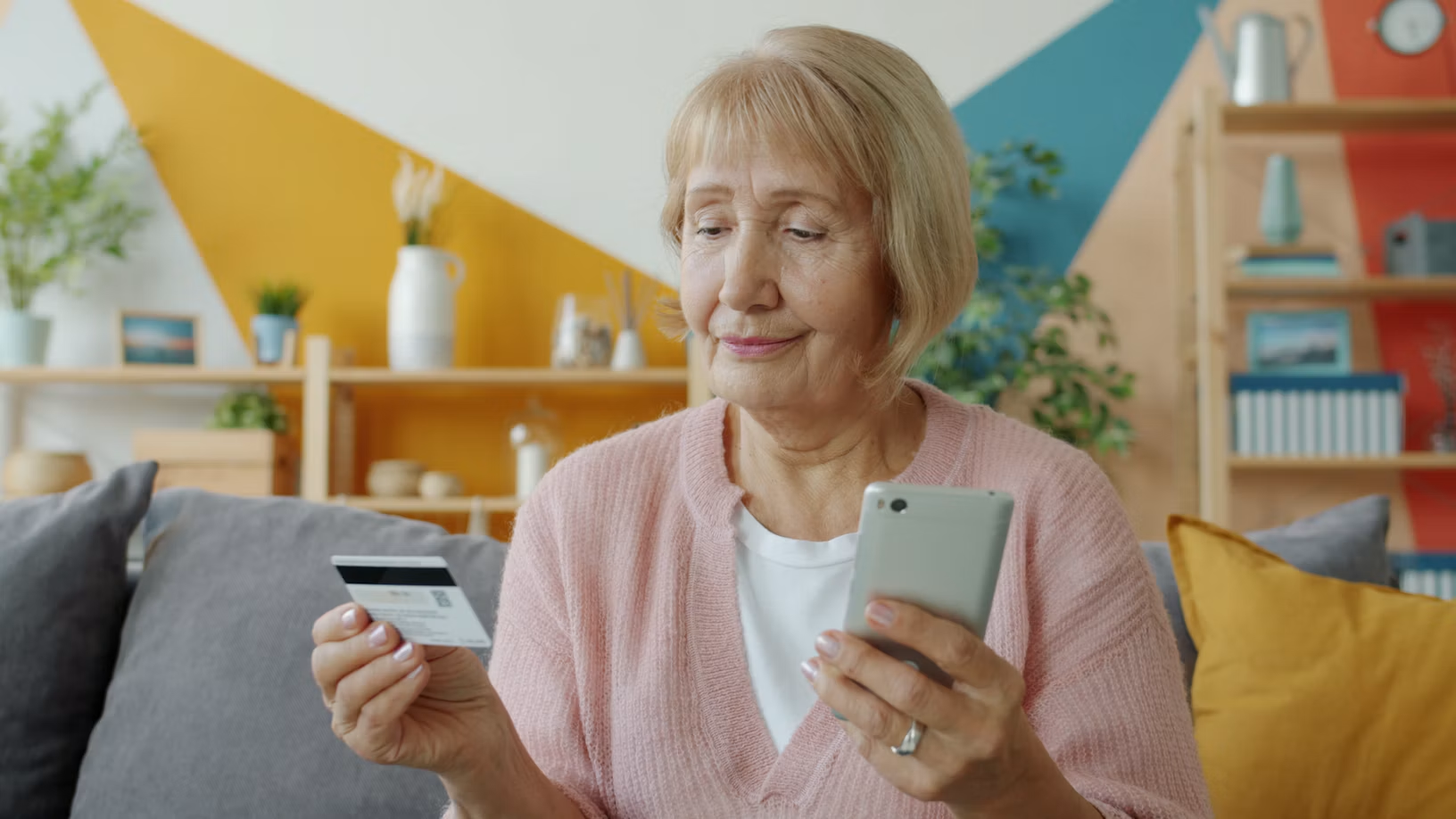 A smiling woman holding her bank card and phone after being paid for her attention